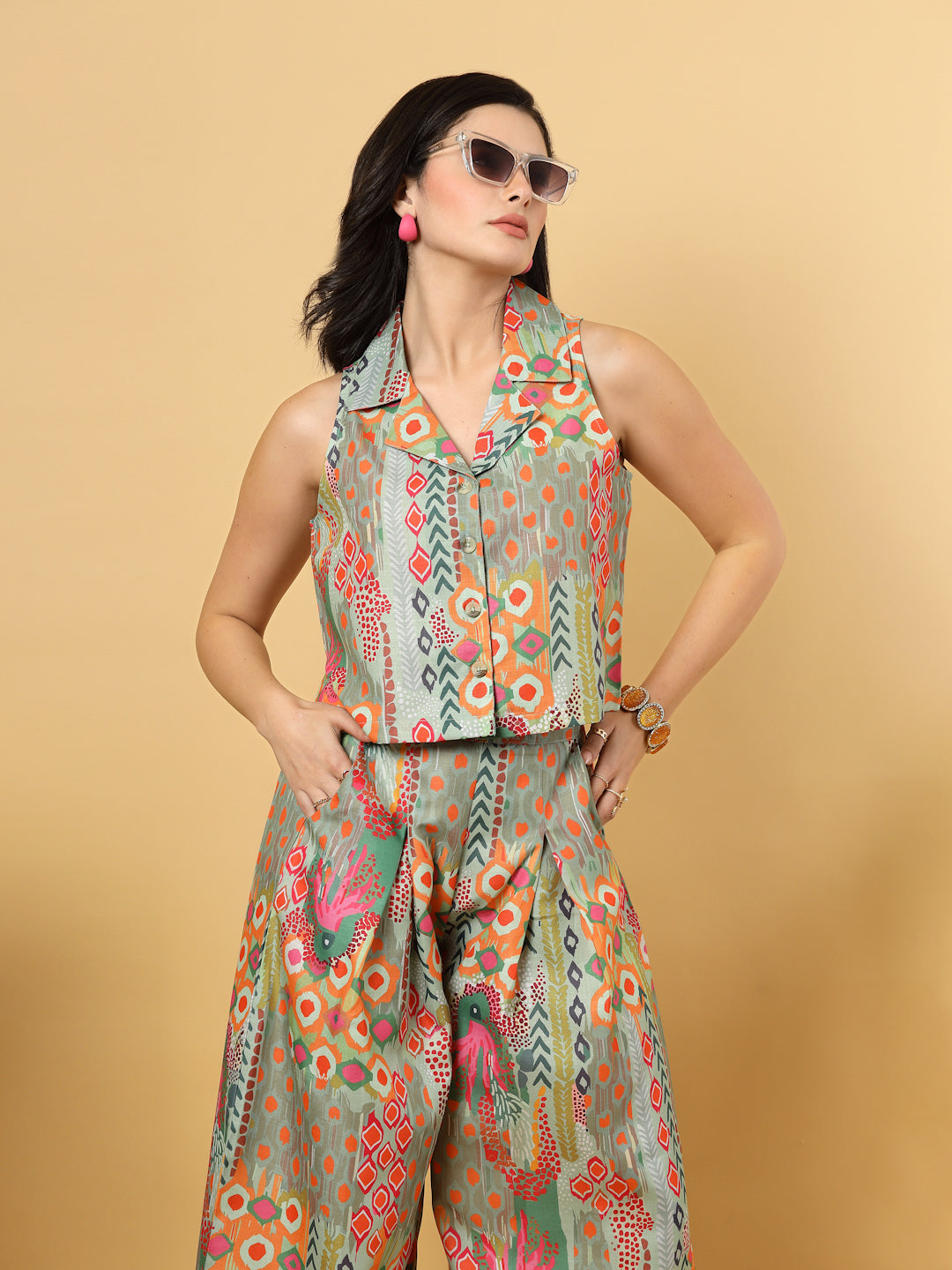 Elevate your ethnic style with this chic 2-piece co-ordinate set for women. The sleeveless top features a beautiful ethnic print with a tailored collar neck and a front button closure for a polished look. Paired with wide-leg pants designed with an elasticated waist, front pleats, and two handy side pockets—this set combines comfort with contemporary flair. Perfect for festive outings or casual gatherings.