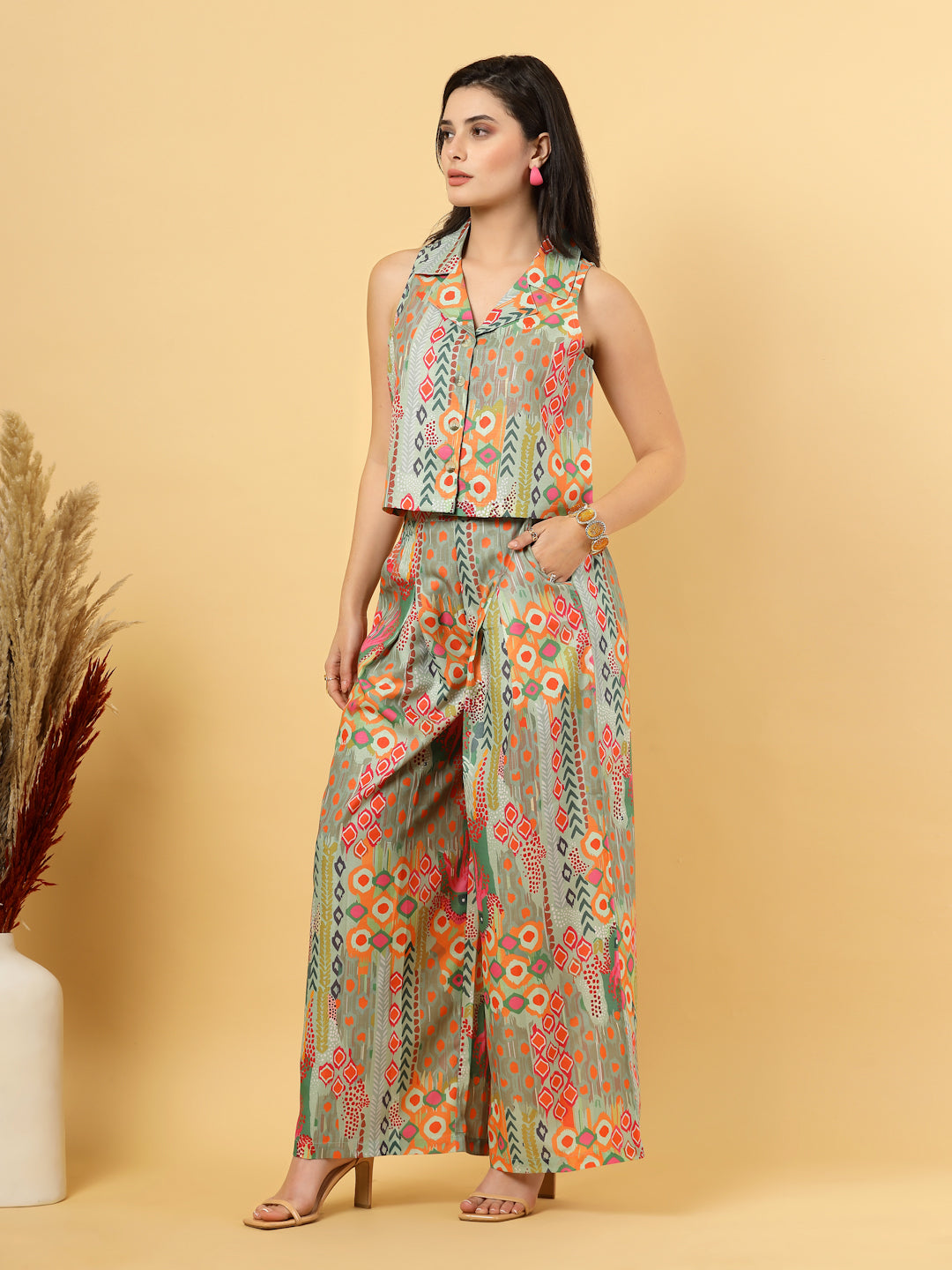 Elevate your ethnic style with this chic 2-piece co-ordinate set for women. The sleeveless top features a beautiful ethnic print with a tailored collar neck and a front button closure for a polished look. Paired with wide-leg pants designed with an elasticated waist, front pleats, and two handy side pockets—this set combines comfort with contemporary flair. Perfect for festive outings or casual gatherings.