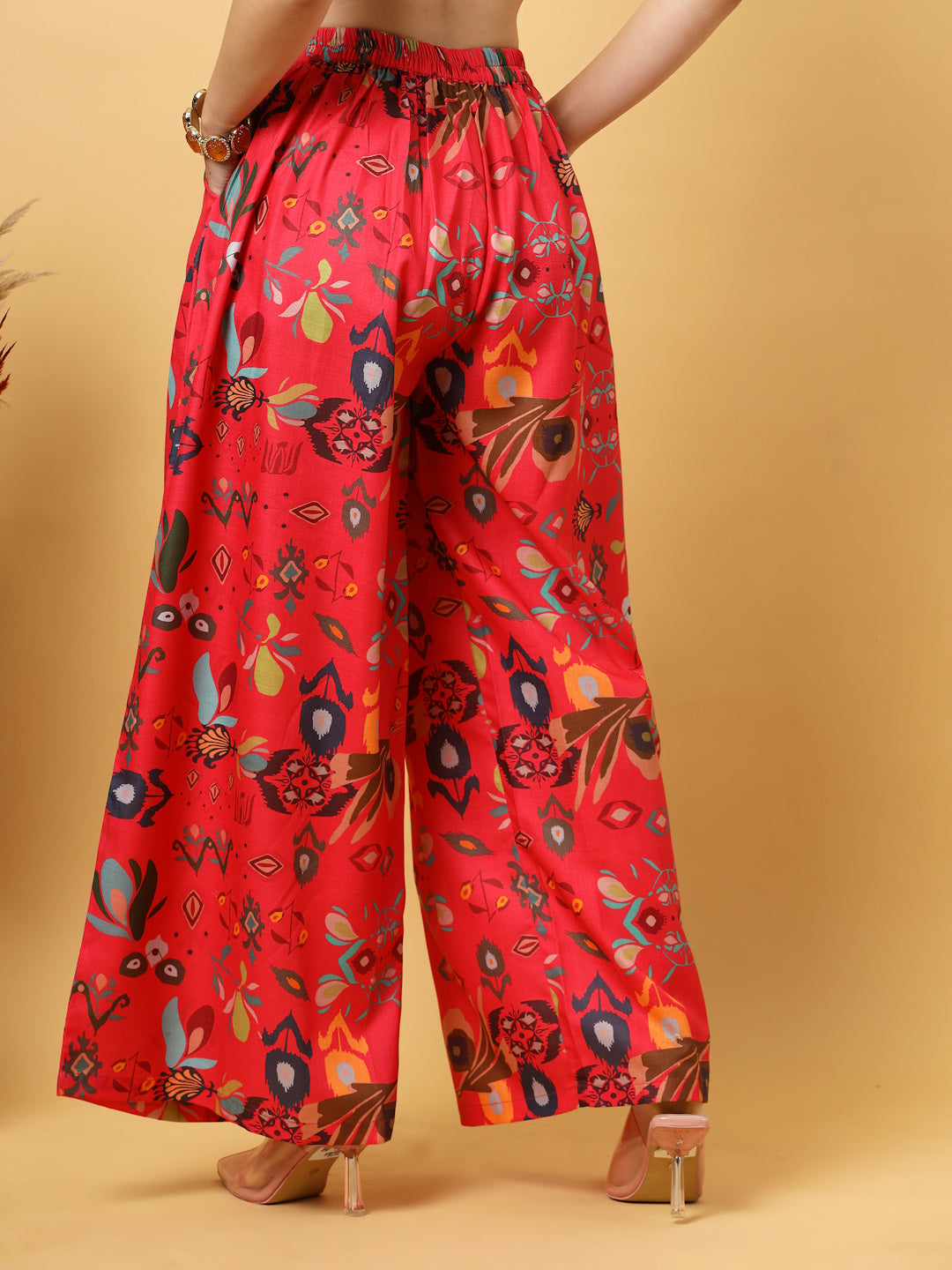 Woman in a red floral wide Leg pants outfit  against a beige background.