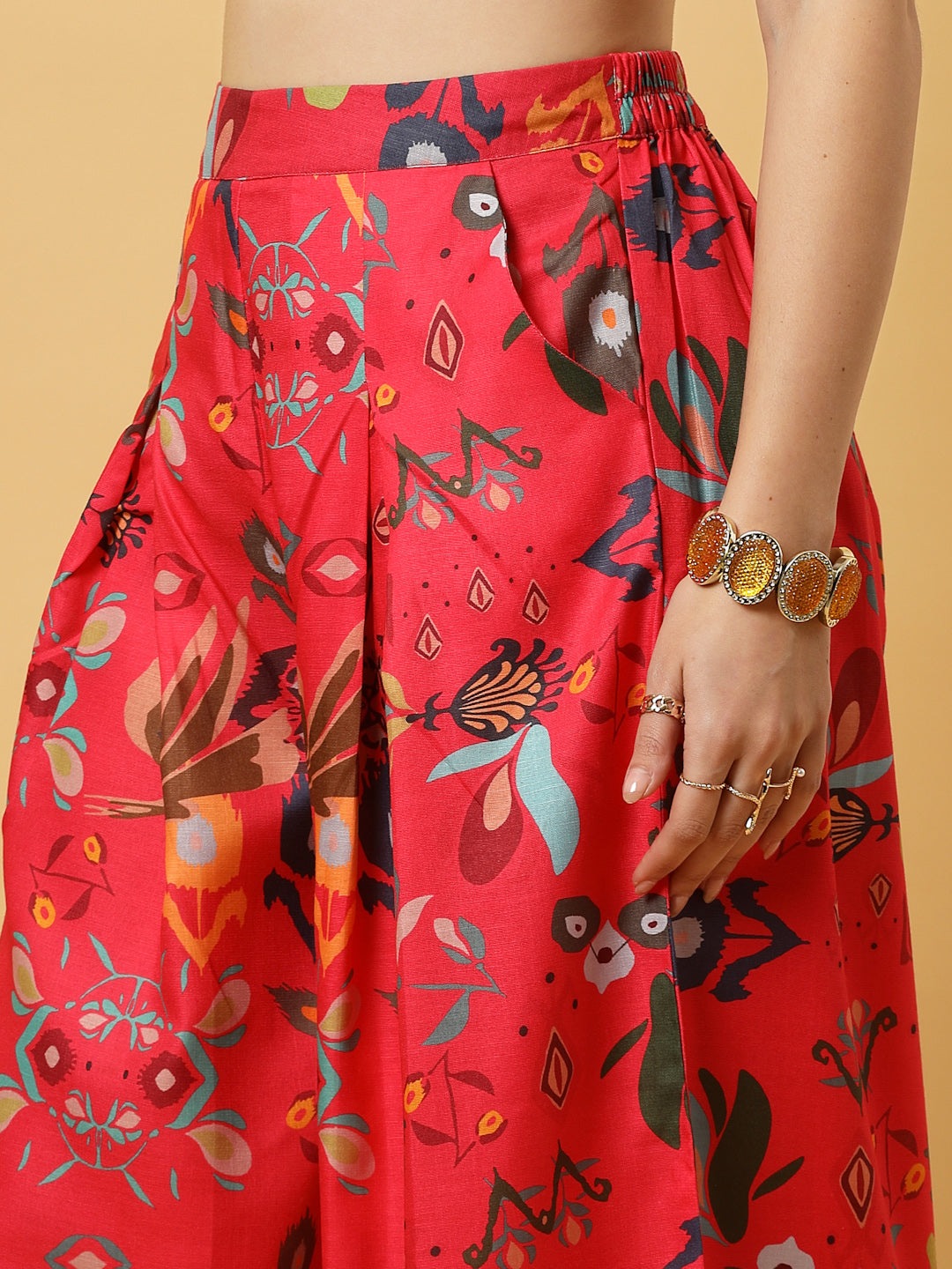 Woman in a red floral wide Leg pants outfit  against a beige background.