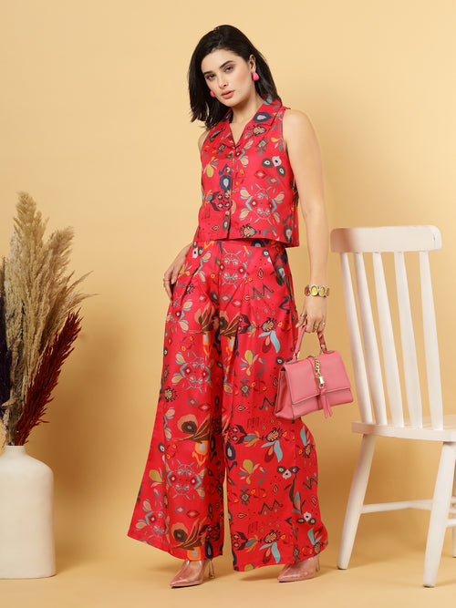 Woman in a red floral top & matching wide Leg pants outfit holding a pink handbag against a beige background.