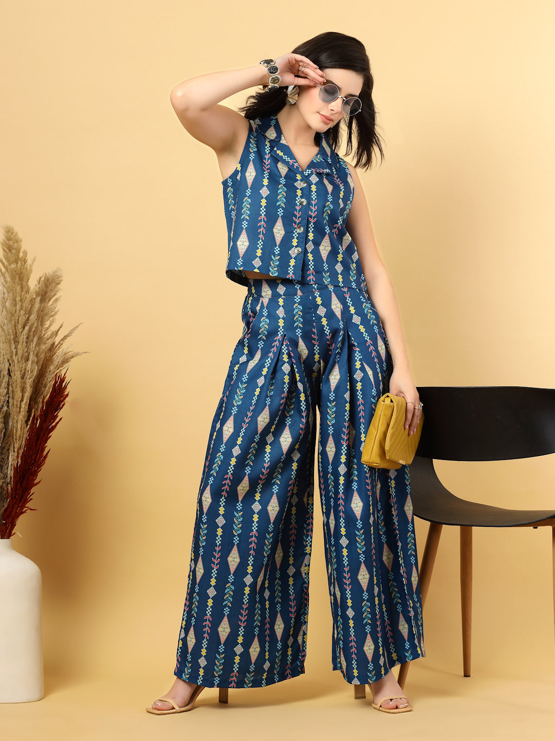 Elevate your ethnic style with this chic 2-piece co-ordinate set for women. The sleeveless top features a beautiful ethnic print with a tailored collar neck and a front button closure for a polished look. Paired with wide-leg pants designed with an elasticated waist, front pleats, and two handy side pockets—this set combines comfort with contemporary flair. Perfect for festive outings or casual gatherings.