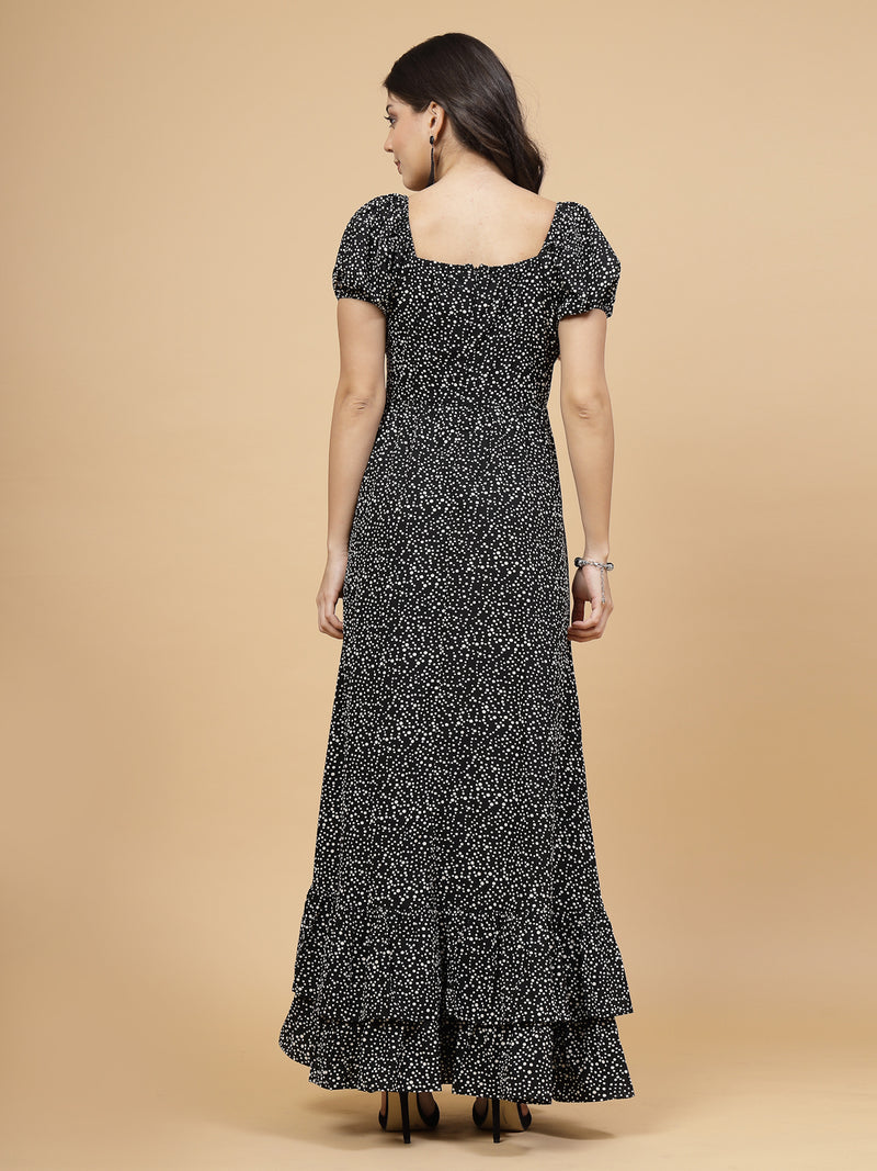 A floor-length casual maxi dress in black dot print. The dress features ruched bust detailing with a drawstring for a customizable fit. It has elasticated shoulders, creating a comfortable and versatile style. The empire waist accentuates the figure, and a double ruffle adds a touch of flair. A front flare with a slit enhances mobility and style. The dress is secured with a zip closure for easy wear.