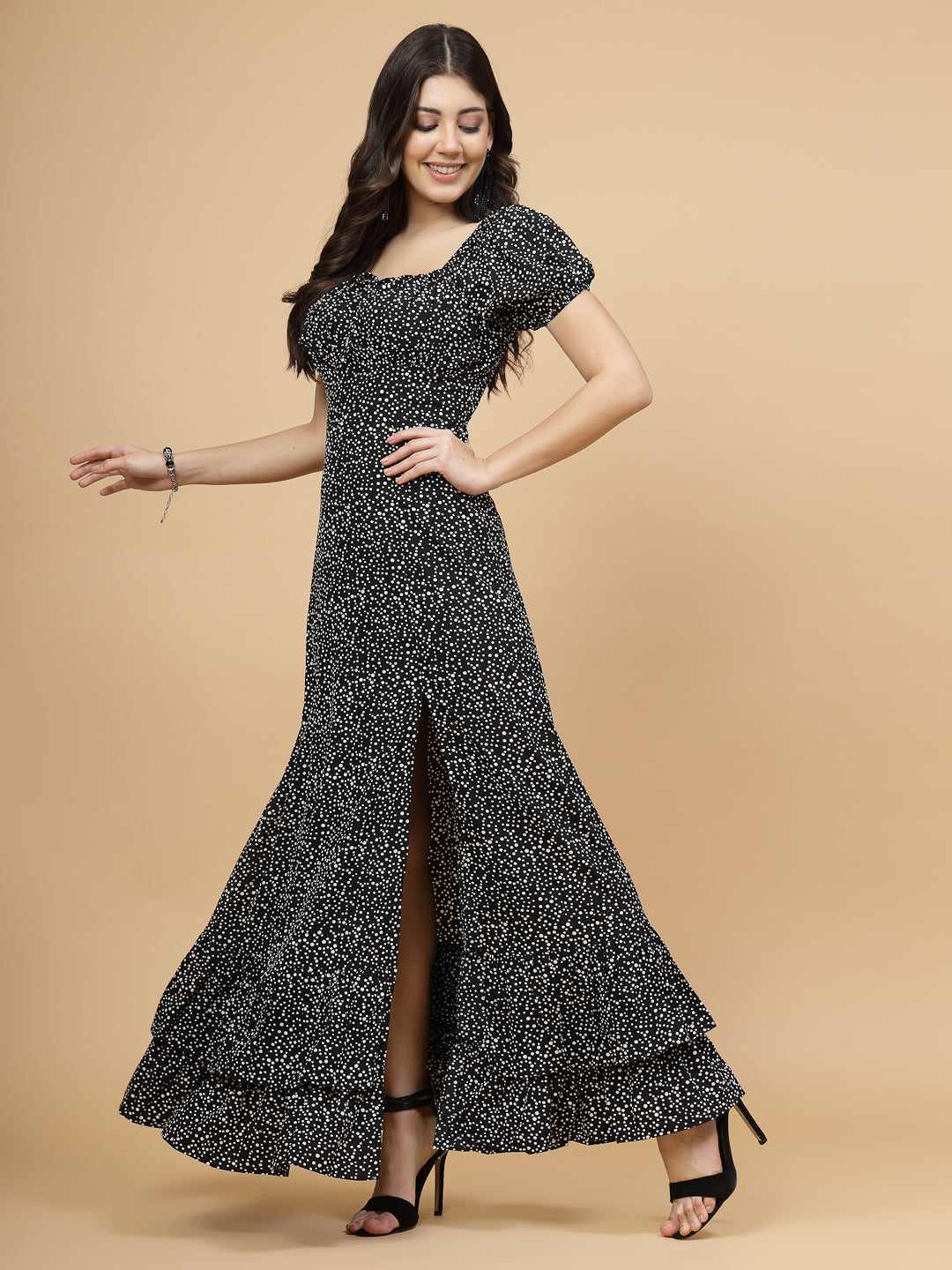 A floor-length casual maxi dress in black dot print. The dress features ruched bust detailing with a drawstring for a customizable fit. It has elasticated shoulders, creating a comfortable and versatile style. The empire waist accentuates the figure, and a double ruffle adds a touch of flair. A front flare with a slit enhances mobility and style. The dress is secured with a zip closure for easy wear.