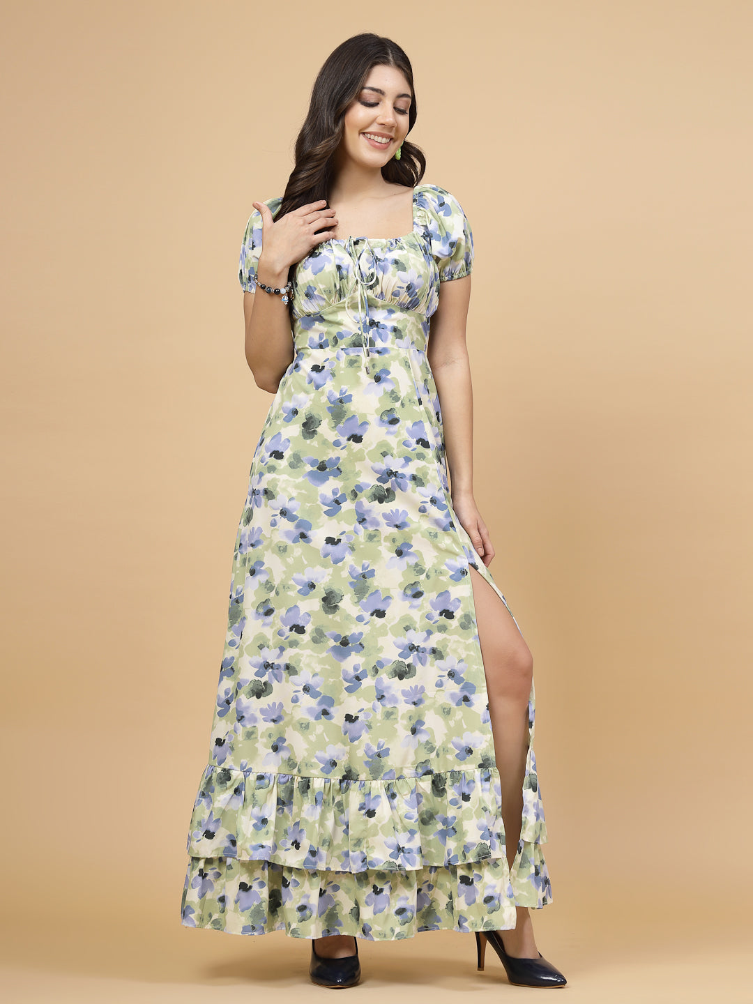A floor-length casual maxi dress in a vibrant green color. The dress features ruched bust detailing with a drawstring for a customizable fit. It has elasticated shoulders, creating a comfortable and versatile style. The empire waist accentuates the figure, and a double ruffle adds a touch of flair. A front flare with a slit enhances mobility and style. The dress is secured with a zip closure for easy wear.