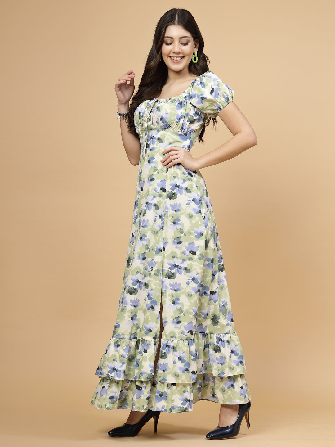A floor-length casual maxi dress in a vibrant green color. The dress features ruched bust detailing with a drawstring for a customizable fit. It has elasticated shoulders, creating a comfortable and versatile style. The empire waist accentuates the figure, and a double ruffle adds a touch of flair. A front flare with a slit enhances mobility and style. The dress is secured with a zip closure for easy wear.