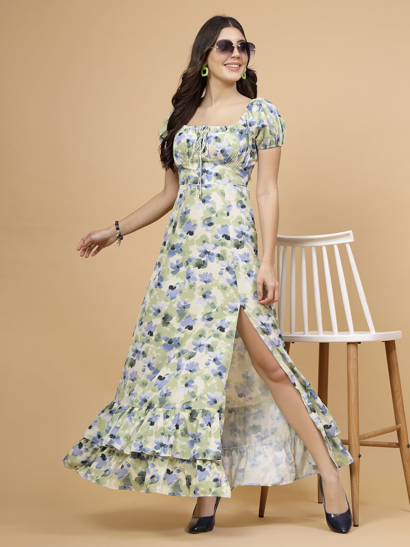 A floor-length casual maxi dress in a vibrant green color. The dress features ruched bust detailing with a drawstring for a customizable fit. It has elasticated shoulders, creating a comfortable and versatile style. The empire waist accentuates the figure, and a double ruffle adds a touch of flair. A front flare with a slit enhances mobility and style. The dress is secured with a zip closure for easy wear.