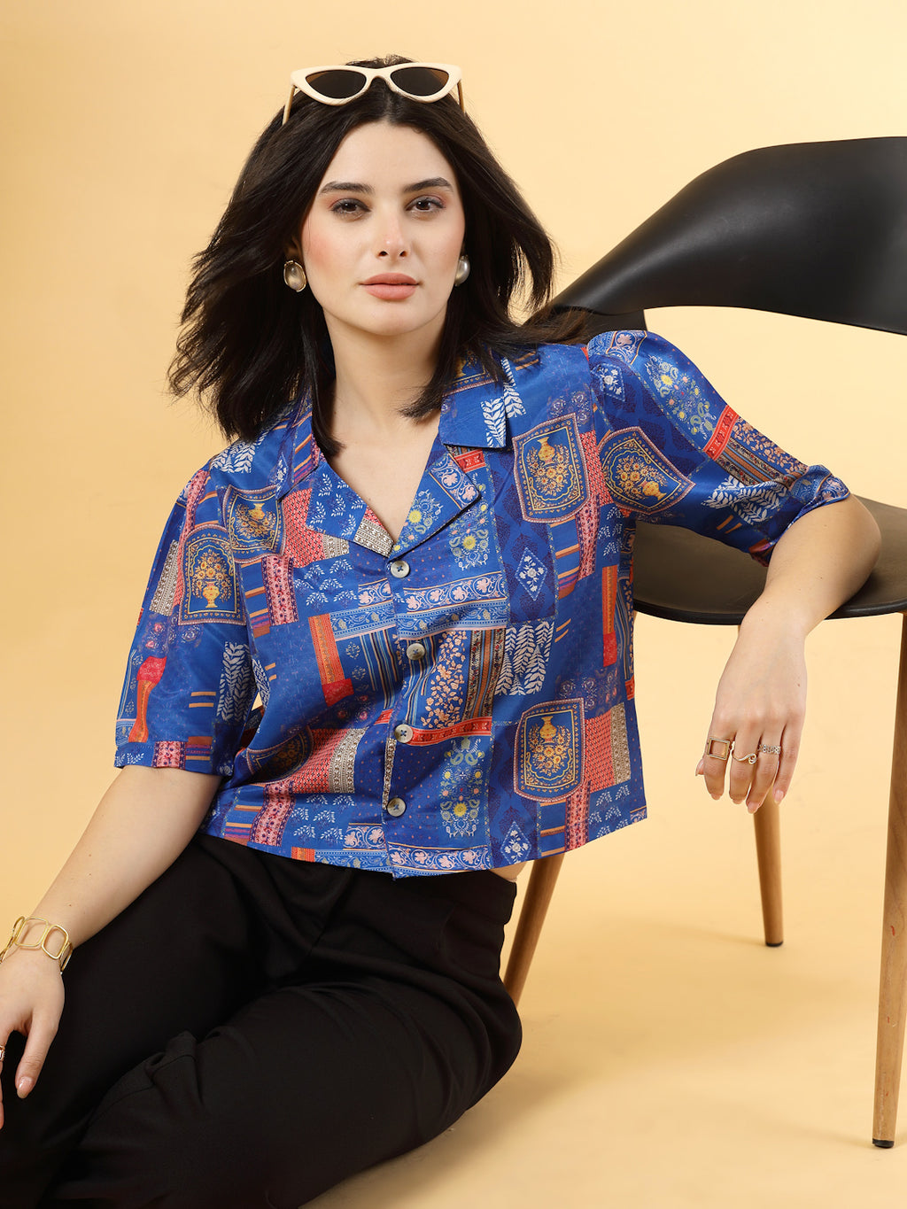 A woman is standing and posing with a blue colour printed coat collar top in a patterned design. 