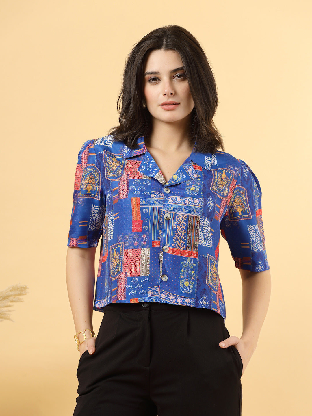 A woman is standing and posing with a blue colour printed coat collar top in a patterned design. 