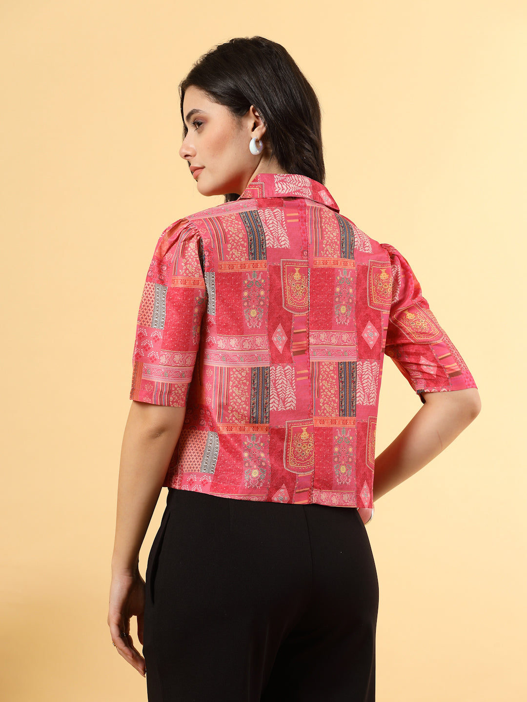 A woman is standing and posing with a printed coat collar top in a patterned design. 