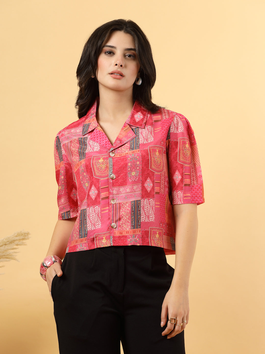 A woman is standing and posing with a printed coat collar top in a patterned design. 