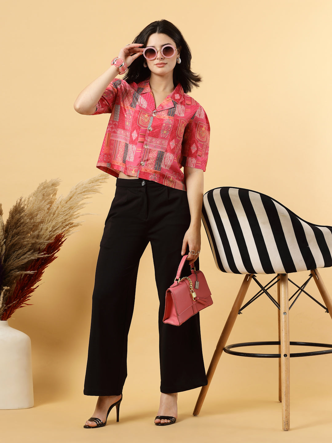 A woman is standing and posing with a printed coat collar top in a patterned design. 
