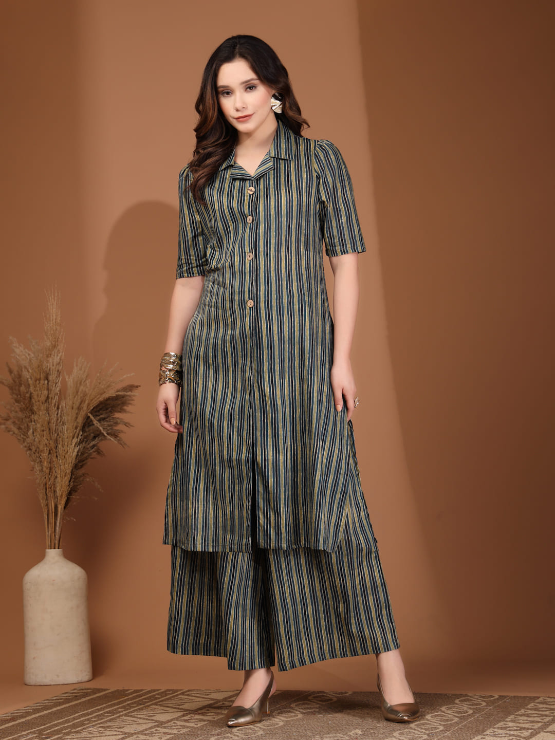 Woman wearing an olive green and navy vertical striped shirt-style tunic top with a front slit and matching wide-leg trousers font view