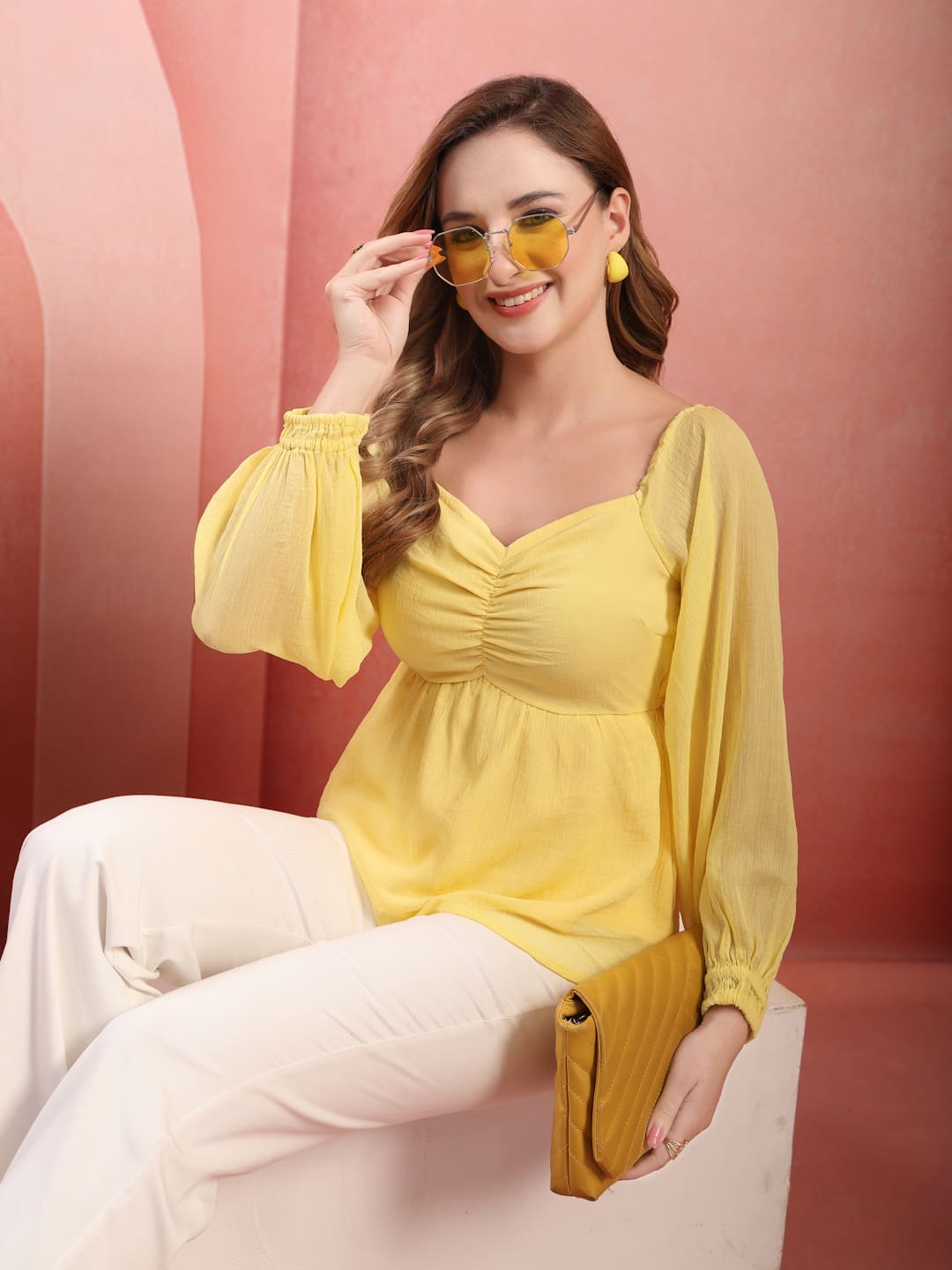 Woman wearing RAASSIO light yellow chiffon top with attached lining and full balloon sleeves sitting view