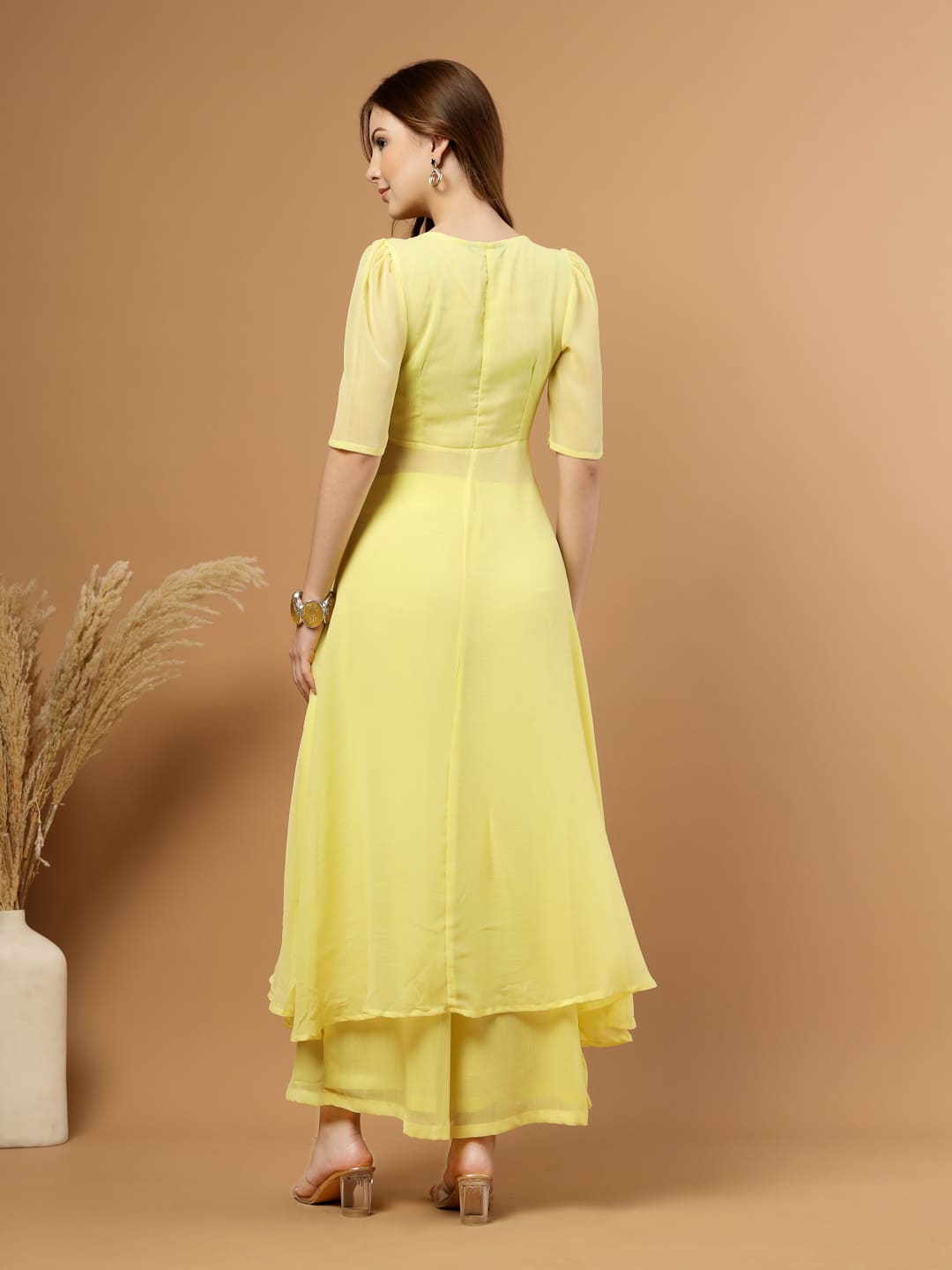 Yellow layered chiffon kurta with cotton lining, lace detailing at neck and flare, paired with flared bottom and side zip closure, back view