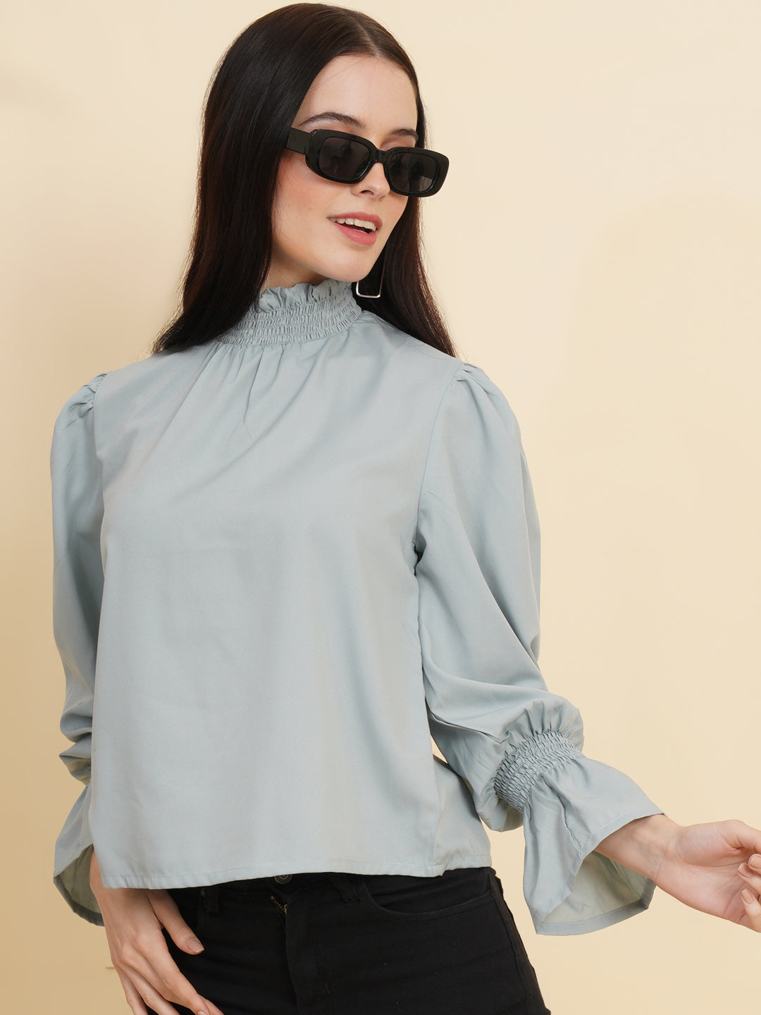 A stylish women's top in a soft shade of grey. The top features smocked detailing on both the full sleeves and the neck band, adding a touch of elegance and texture to the design.