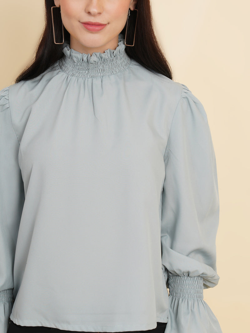 A stylish women's top in a soft shade of grey. The top features smocked detailing on both the full sleeves and the neck band, adding a touch of elegance and texture to the design.