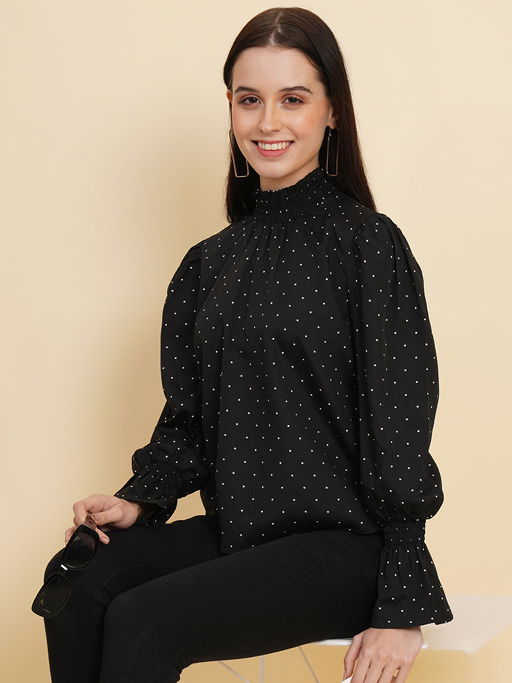 An elegant black women's top with a stylish dotted print. The top features a smocked neck and sleeves, adding a touch of sophistication and charm to your outfit