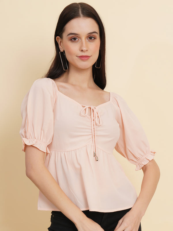 A peach-colored solid peplum top for women with ruched waist detailing. The top features a flattering peplum silhouette that cinches at the waist and flares out, creating a feminine and stylish look. The peach color adds a soft and elegant touch to the garment.