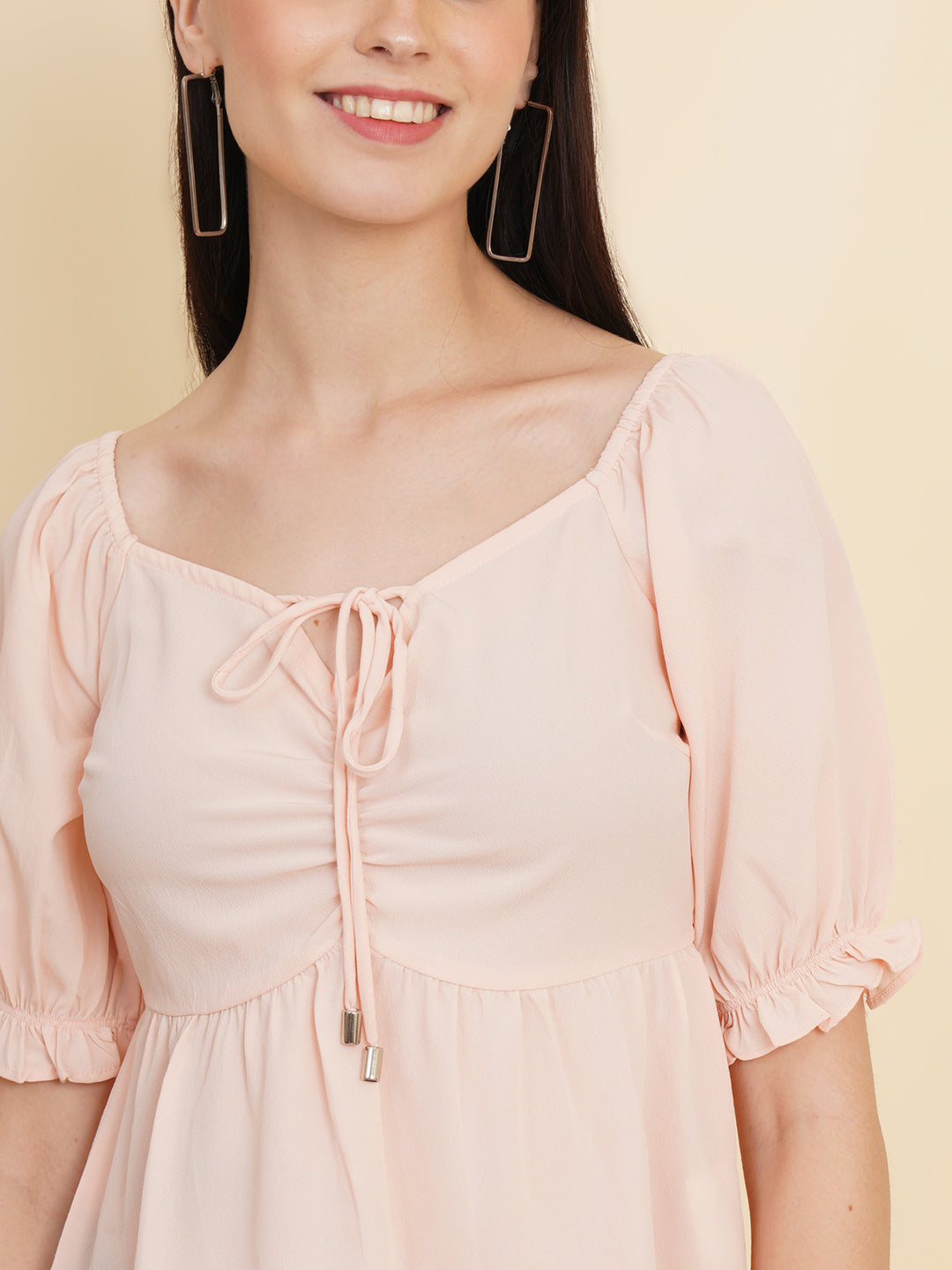 A peach-colored solid peplum top for women with ruched waist detailing. The top features a flattering peplum silhouette that cinches at the waist and flares out, creating a feminine and stylish look. The peach color adds a soft and elegant touch to the garment.