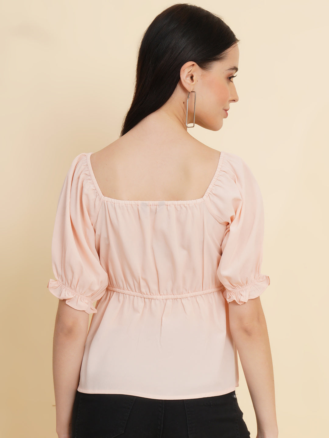 A peach-colored solid peplum top for women with ruched waist detailing. The top features a flattering peplum silhouette that cinches at the waist and flares out, creating a feminine and stylish look. The peach color adds a soft and elegant touch to the garment.