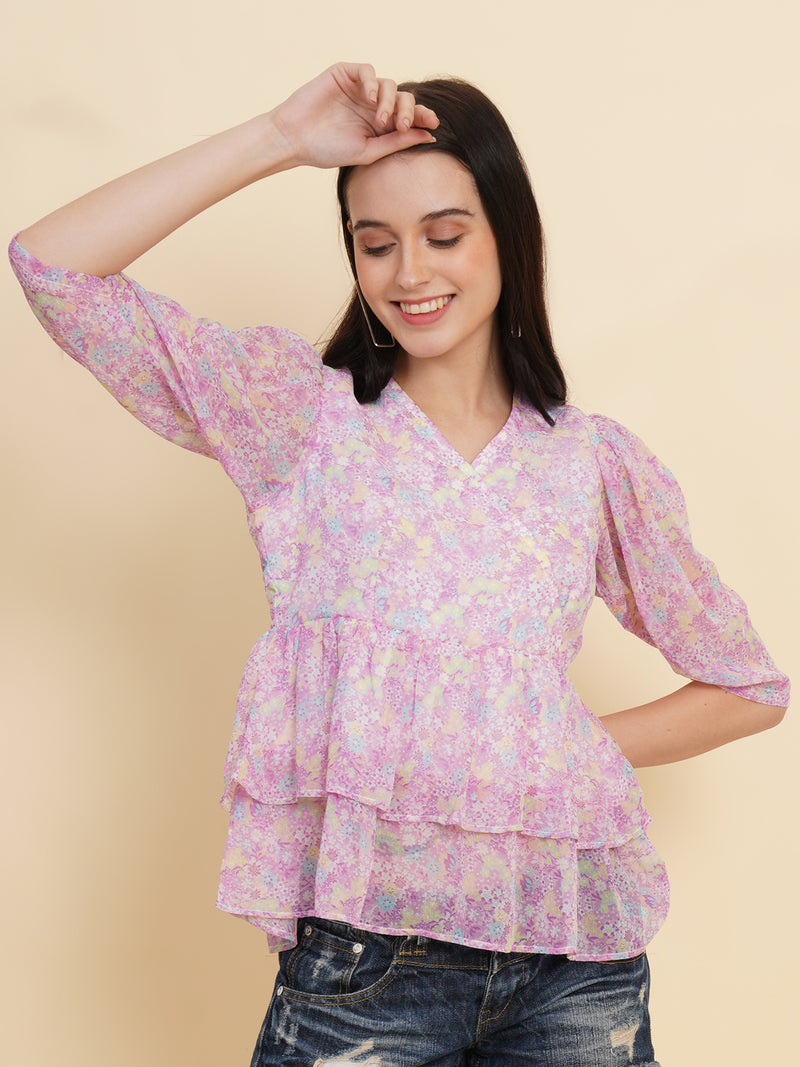 A vibrant purple women's top adorned with beautiful floral patterns. It features double ruffle detailing, creating an elegant and feminine look. The top is fully lined, providing comfort and a smooth fit. Perfect for adding a touch of color and style to any outfit