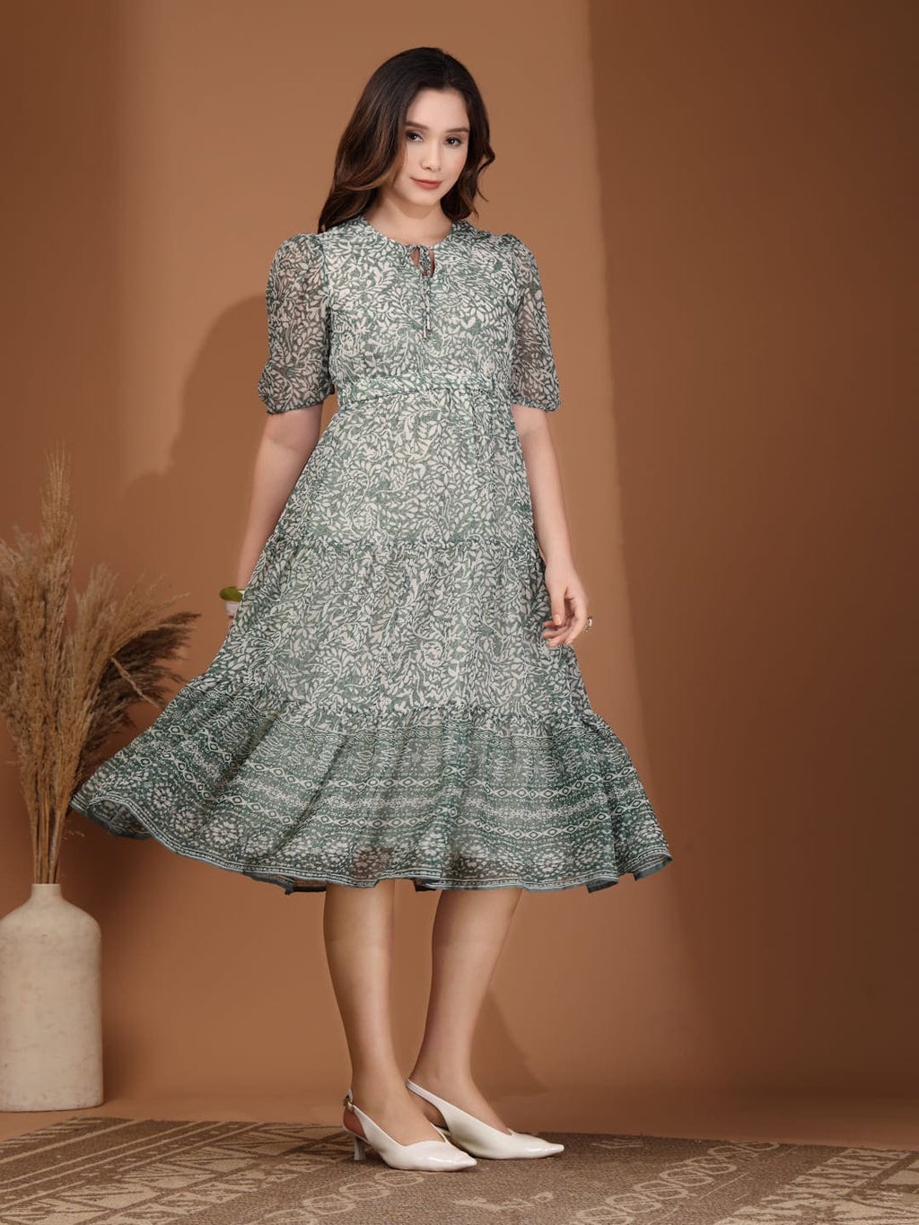 Woman wearing RAASSIO sage green floral printed chiffon tiered midi dress with attached lining left side view
