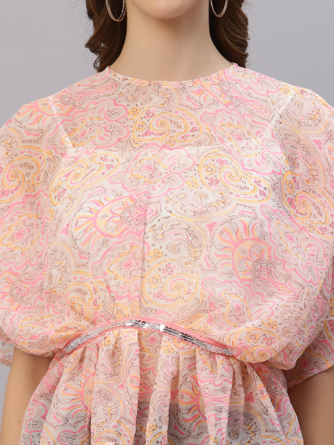 This top features a lightweight and flowy chiffon material that drapes beautifully over the body. The oversized design allows for a comfortable and relaxed fit, while the attached cami provides extra coverage and support. The embellished waist band adds a touch of sparkle and elegance, accentuating the waistline and creating a flattering silhouette. This top is perfect for a variety of occasions, from casual outings to formal events. Pair it with skinny jeans and heels for a chic and stylish look.