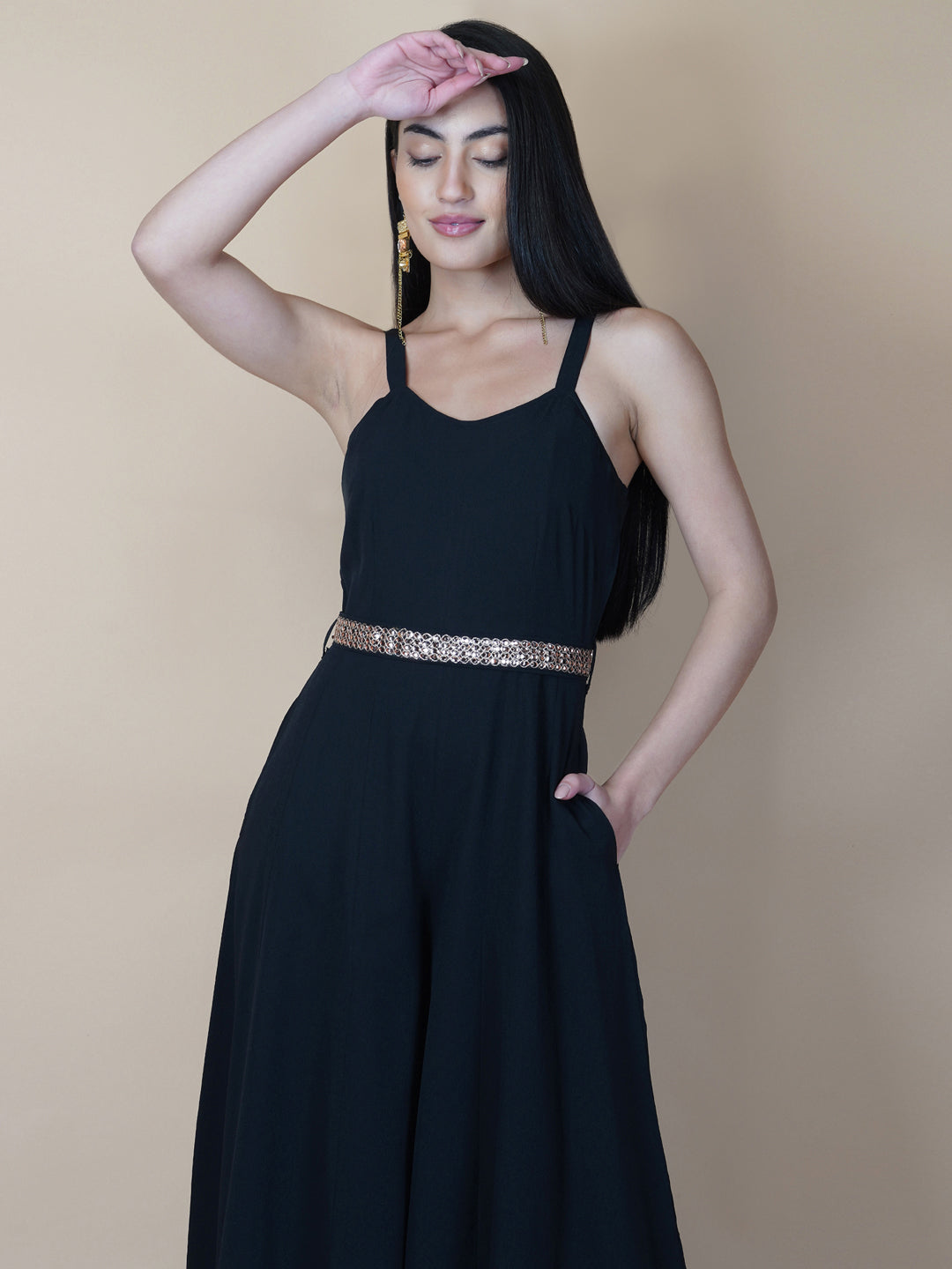 This black solid fit and flare women jumpsuit with an attached belt is a fashionable one-piece garment that combines the comfort of pants with the elegance of a dress. This jumpsuit features a fitted top that flares out into wide-leg pants, creating a flattering silhouette that accentuates the waist and elongates the legs.