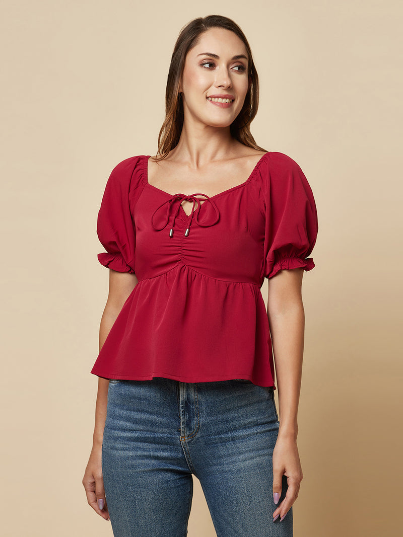 A Burgundy Solid Ruched Waist Peplum Top for Women is a stylish and flattering garment that is perfect for various occasions. The top features a beautiful shade of burgundy, which is perfect for adding a pop of color to any outfit. The ruched waistline creates a slimming effect, accentuating the natural curves of the body. The peplum detail adds a feminine and stylish touch to the design, making it perfect for a night out or a formal event.