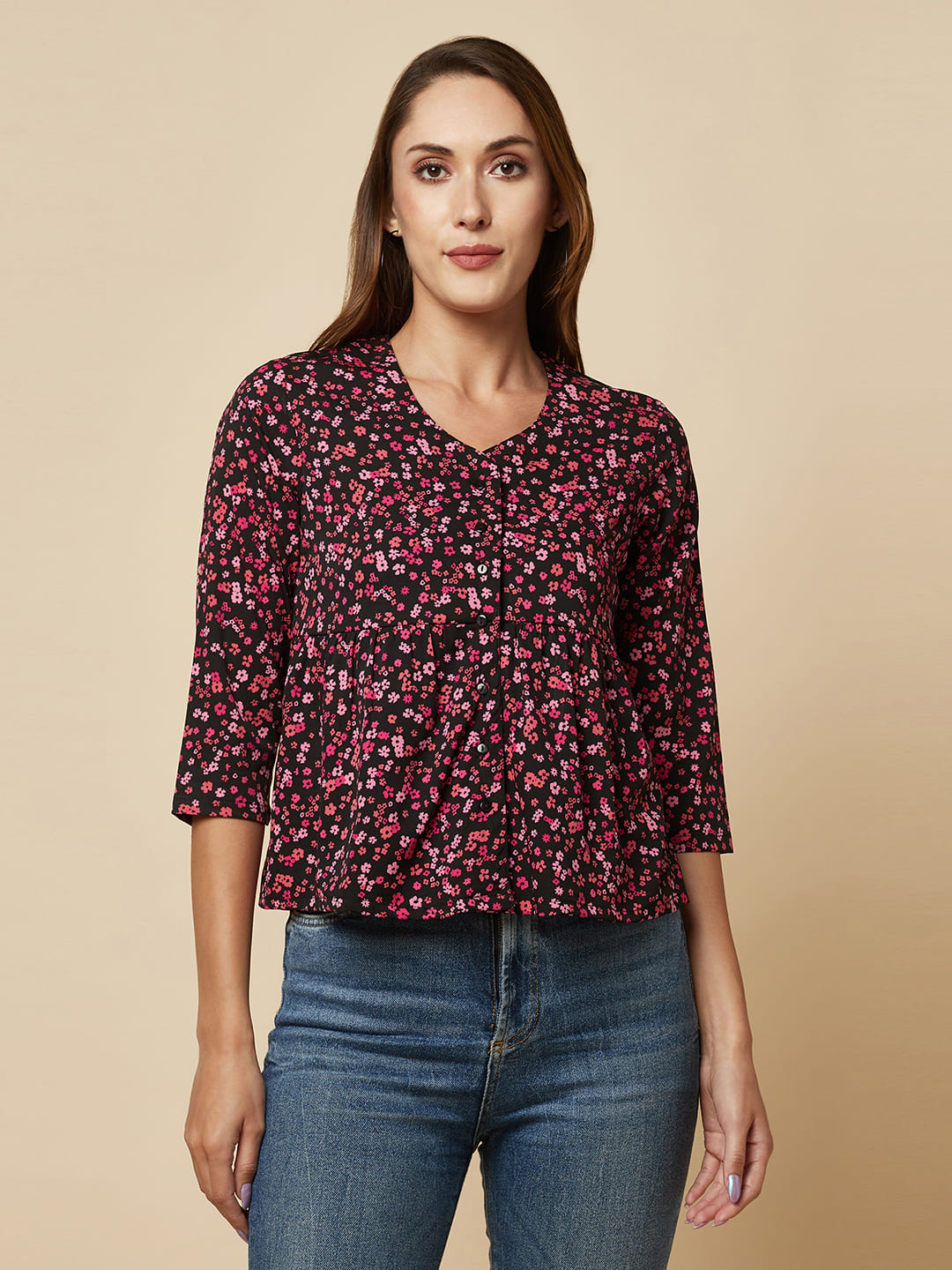 A pink floral printed top with a front placket and ruched bust line is a stylish and elegant piece of clothing. The top has a simple and classic design with a front placket that adds a touch of sophistication to the outfit. The ruched bust line creates a flattering and feminine look, enhancing the wearer's curves. 