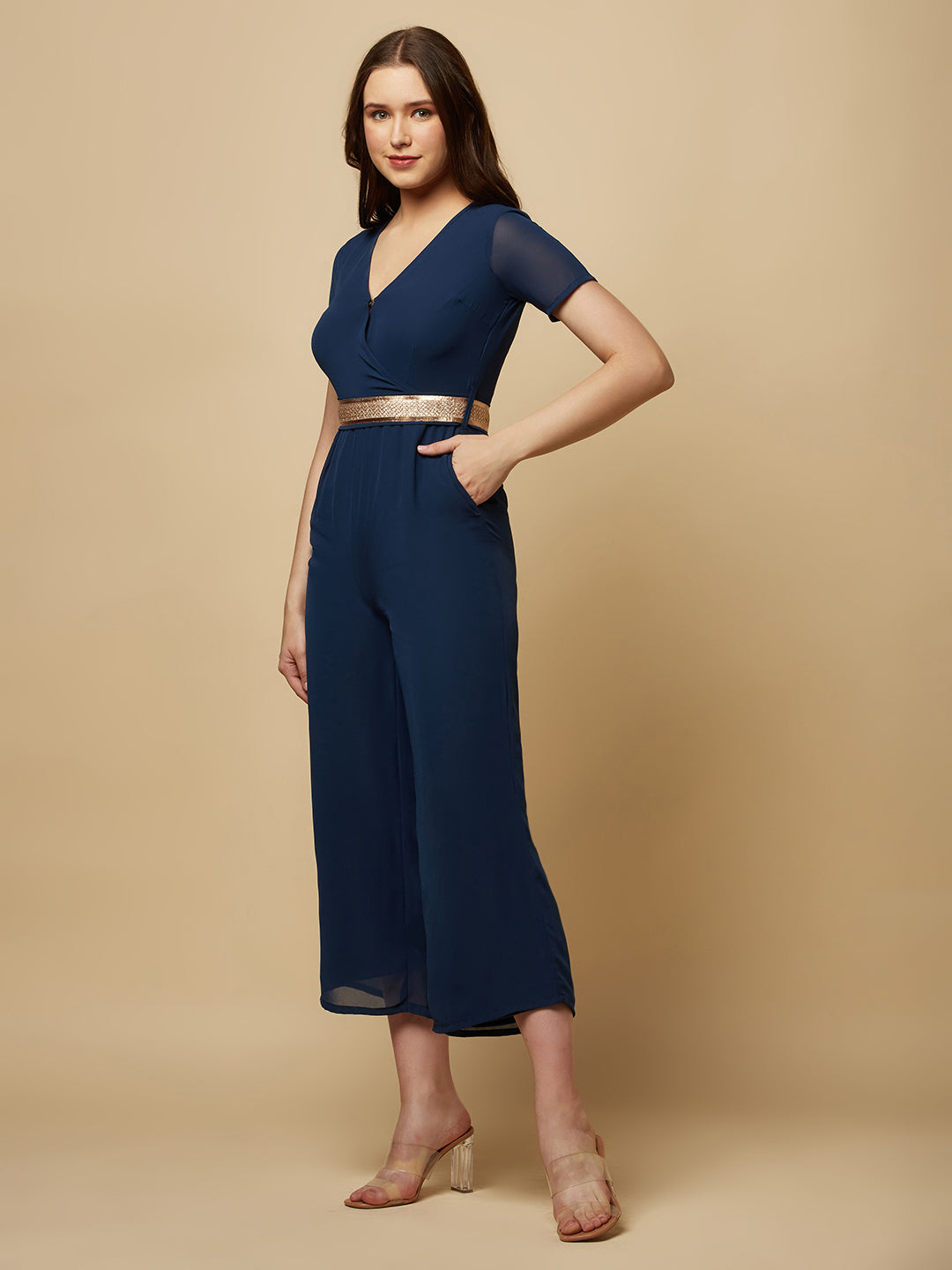 An Angrakkha style jumpsuit has a wrap-like design with a V-neckline and a side tie or belt closure. The jumpsuit may have a fitted bodice with wide-leg pants design.  The jumpsuit  is made from  polyester fabric with attached lining.  Golden Belt  clinches waist and gives it a more feminine look. Overall, a yellow color solid Angrakkha style women's jumpsuit with a belt is a stylish and comfortable outfit option for a variety of occasions.