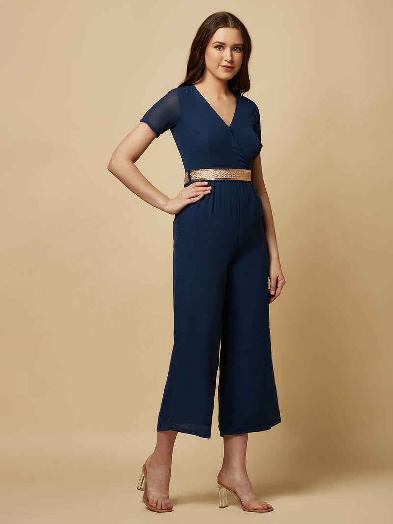 An Angrakkha style jumpsuit has a wrap-like design with a V-neckline and a side tie or belt closure. The jumpsuit may have a fitted bodice with wide-leg pants design.  The jumpsuit  is made from  polyester fabric with attached lining.  Golden Belt  clinches waist and gives it a more feminine look. Overall, a yellow color solid Angrakkha style women's jumpsuit with a belt is a stylish and comfortable outfit option for a variety of occasions.