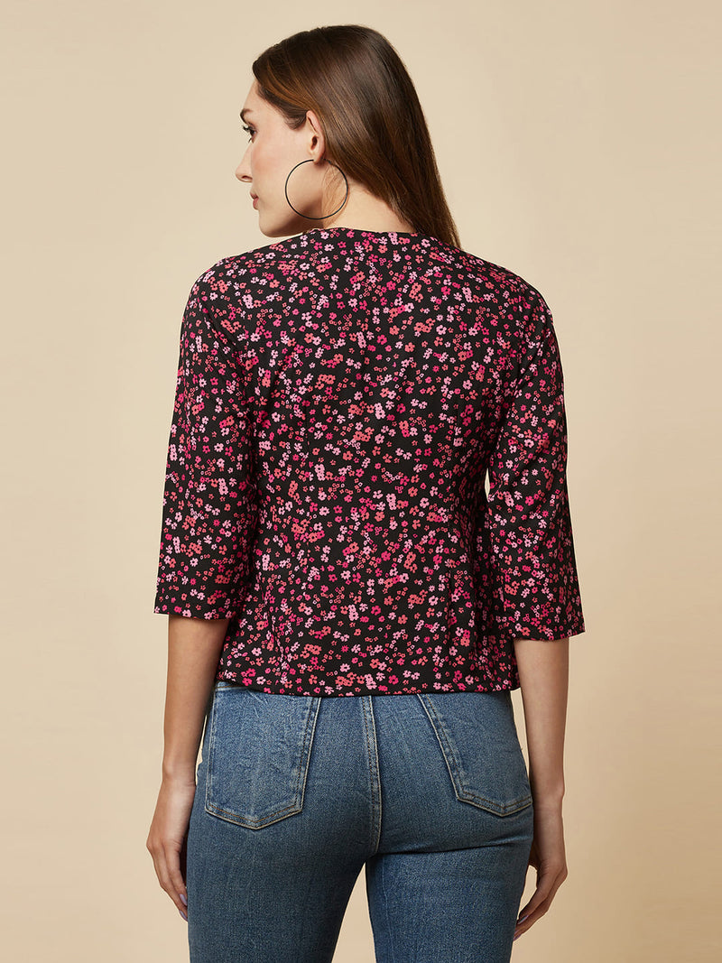 A pink floral printed top with a front placket and ruched bust line is a stylish and elegant piece of clothing. The top has a simple and classic design with a front placket that adds a touch of sophistication to the outfit. The ruched bust line creates a flattering and feminine look, enhancing the wearer's curves. 