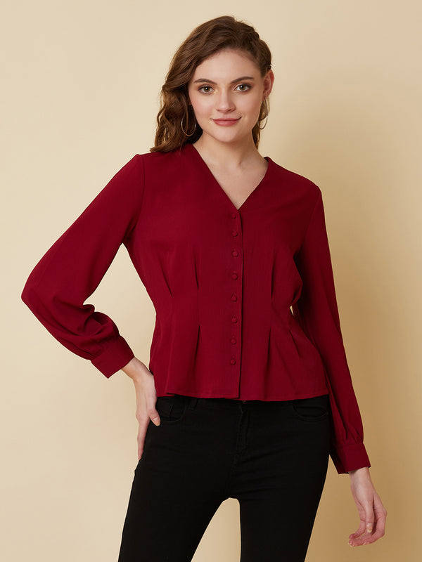 This top is made of a burgundy colored fabric and features a solid waist and pleated detailing. The waist creates a flattering silhouette by accentuating the waistline, while the pleats add texture and dimension to the top. The neckline is V shape and the sleeves are full, making this top perfect for both casual and formal occasions. It can be paired with jeans or dress pants, and can be dressed up or down depending on the occasion.