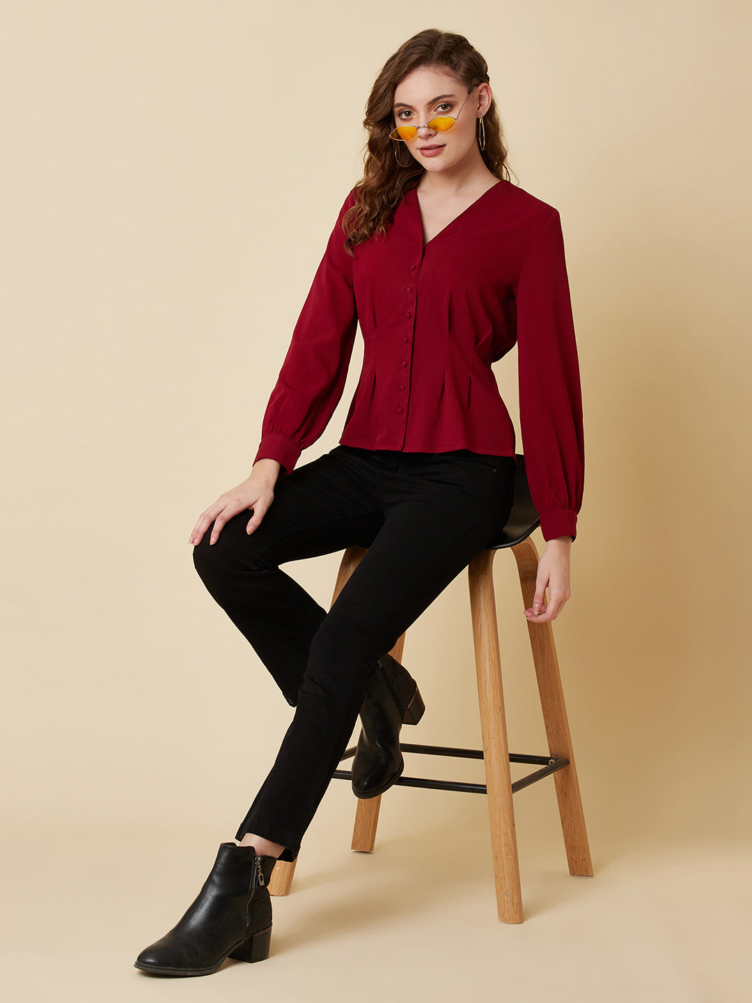 This top is made of a burgundy colored fabric and features a solid waist and pleated detailing. The waist creates a flattering silhouette by accentuating the waistline, while the pleats add texture and dimension to the top. The neckline is V shape and the sleeves are full, making this top perfect for both casual and formal occasions. It can be paired with jeans or dress pants, and can be dressed up or down depending on the occasion.