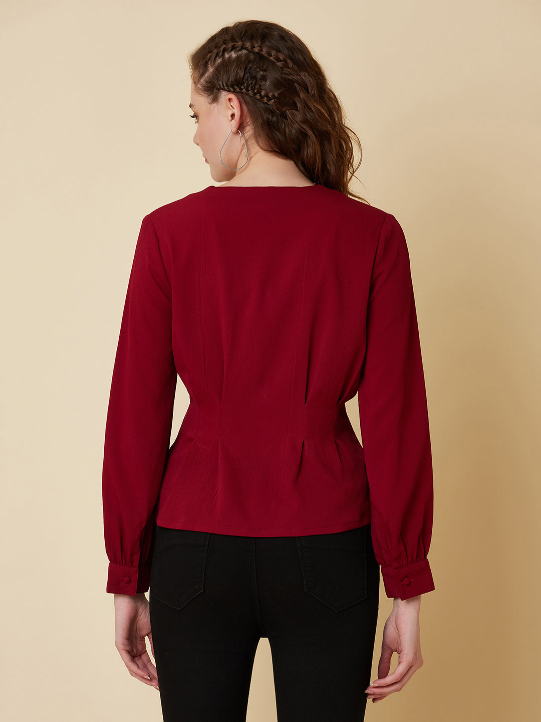 This top is made of a burgundy colored fabric and features a solid waist and pleated detailing. The waist creates a flattering silhouette by accentuating the waistline, while the pleats add texture and dimension to the top. The neckline is V shape and the sleeves are full, making this top perfect for both casual and formal occasions. It can be paired with jeans or dress pants, and can be dressed up or down depending on the occasion.