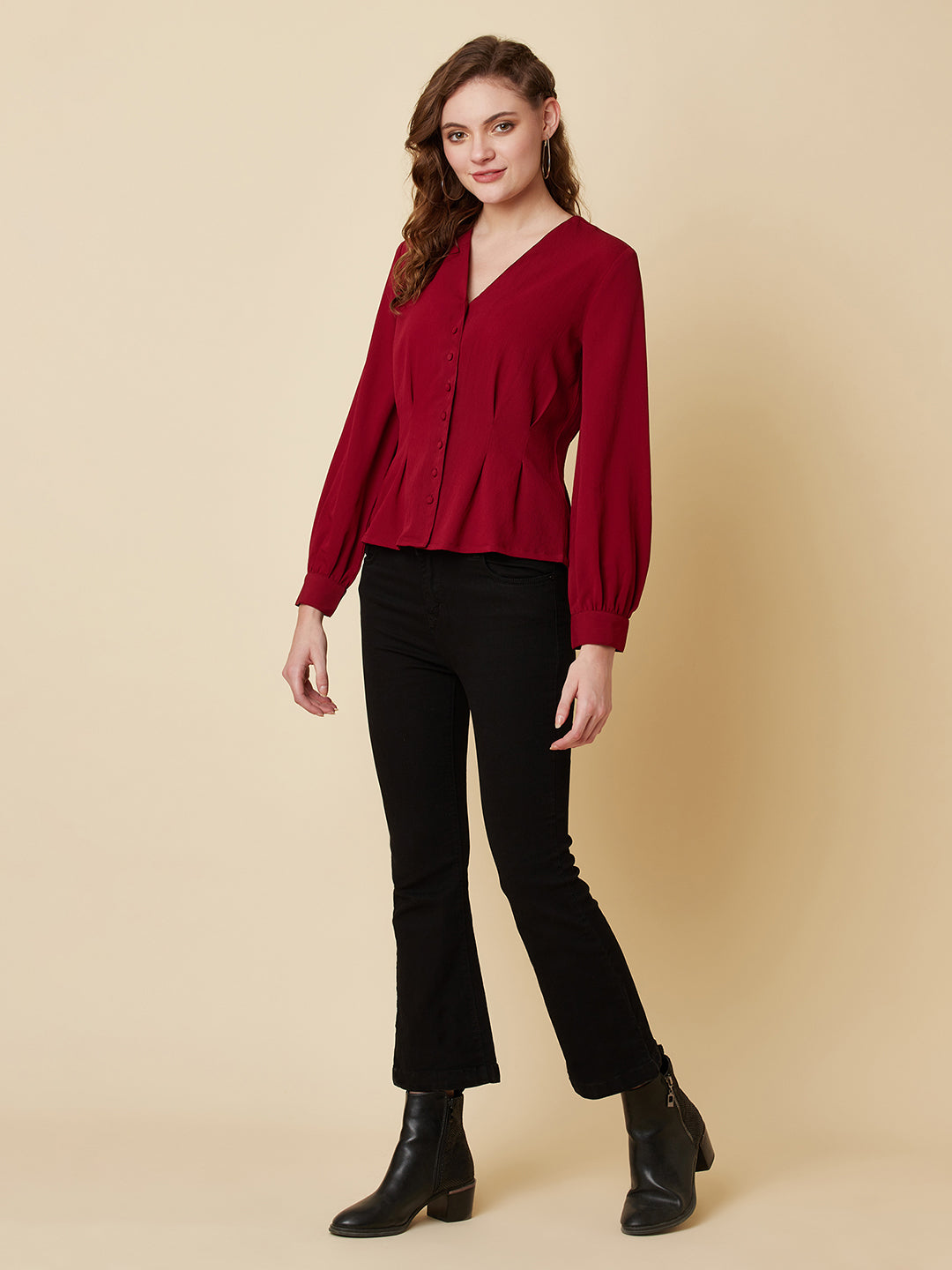 This top is made of a burgundy colored fabric and features a solid waist and pleated detailing. The waist creates a flattering silhouette by accentuating the waistline, while the pleats add texture and dimension to the top. The neckline is V shape and the sleeves are full, making this top perfect for both casual and formal occasions. It can be paired with jeans or dress pants, and can be dressed up or down depending on the occasion.