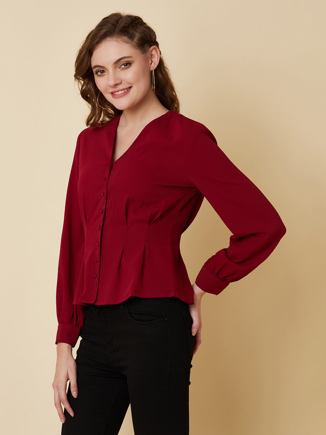 This top is made of a burgundy colored fabric and features a solid waist and pleated detailing. The waist creates a flattering silhouette by accentuating the waistline, while the pleats add texture and dimension to the top. The neckline is V shape and the sleeves are full, making this top perfect for both casual and formal occasions. It can be paired with jeans or dress pants, and can be dressed up or down depending on the occasion.