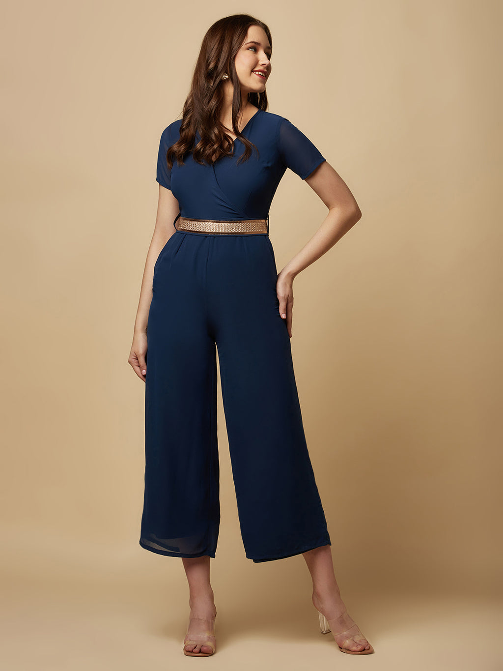An Angrakkha style jumpsuit has a wrap-like design with a V-neckline and a side tie or belt closure. The jumpsuit may have a fitted bodice with wide-leg pants design.  The jumpsuit  is made from  polyester fabric with attached lining.  Golden Belt  clinches waist and gives it a more feminine look. Overall, a yellow color solid Angrakkha style women's jumpsuit with a belt is a stylish and comfortable outfit option for a variety of occasions.